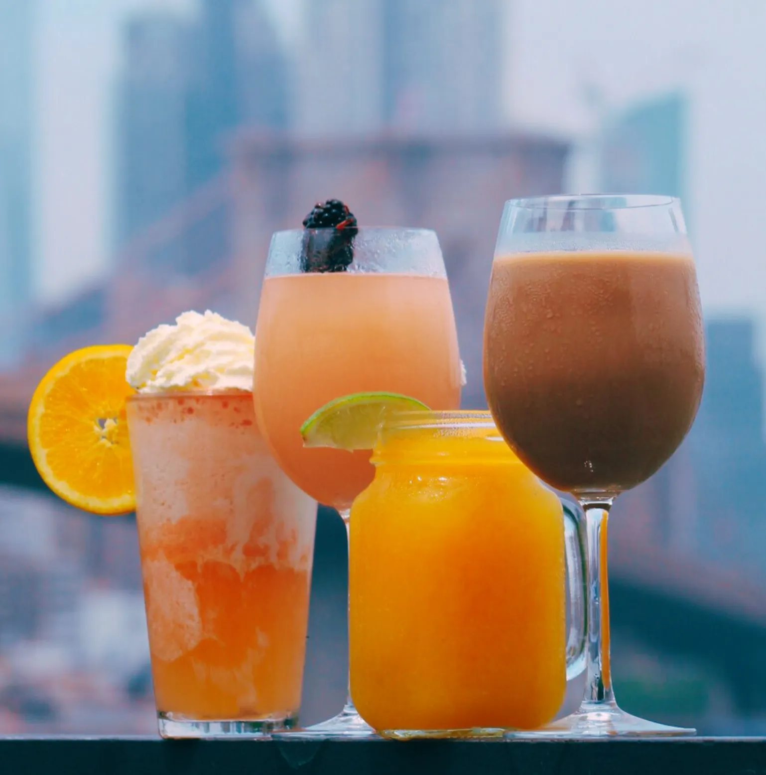 Four cocktails with the NYC skyline in the background