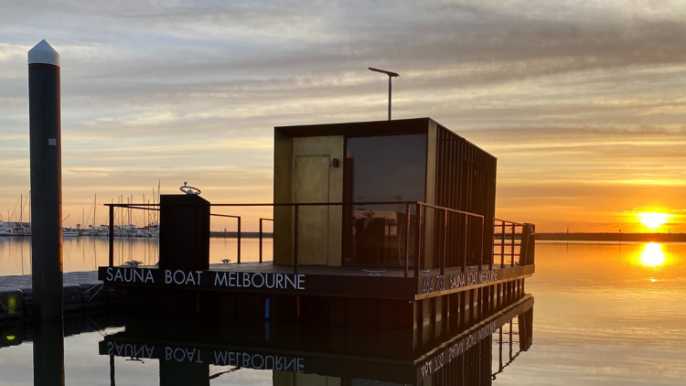 A floating sauna boat at sunset.