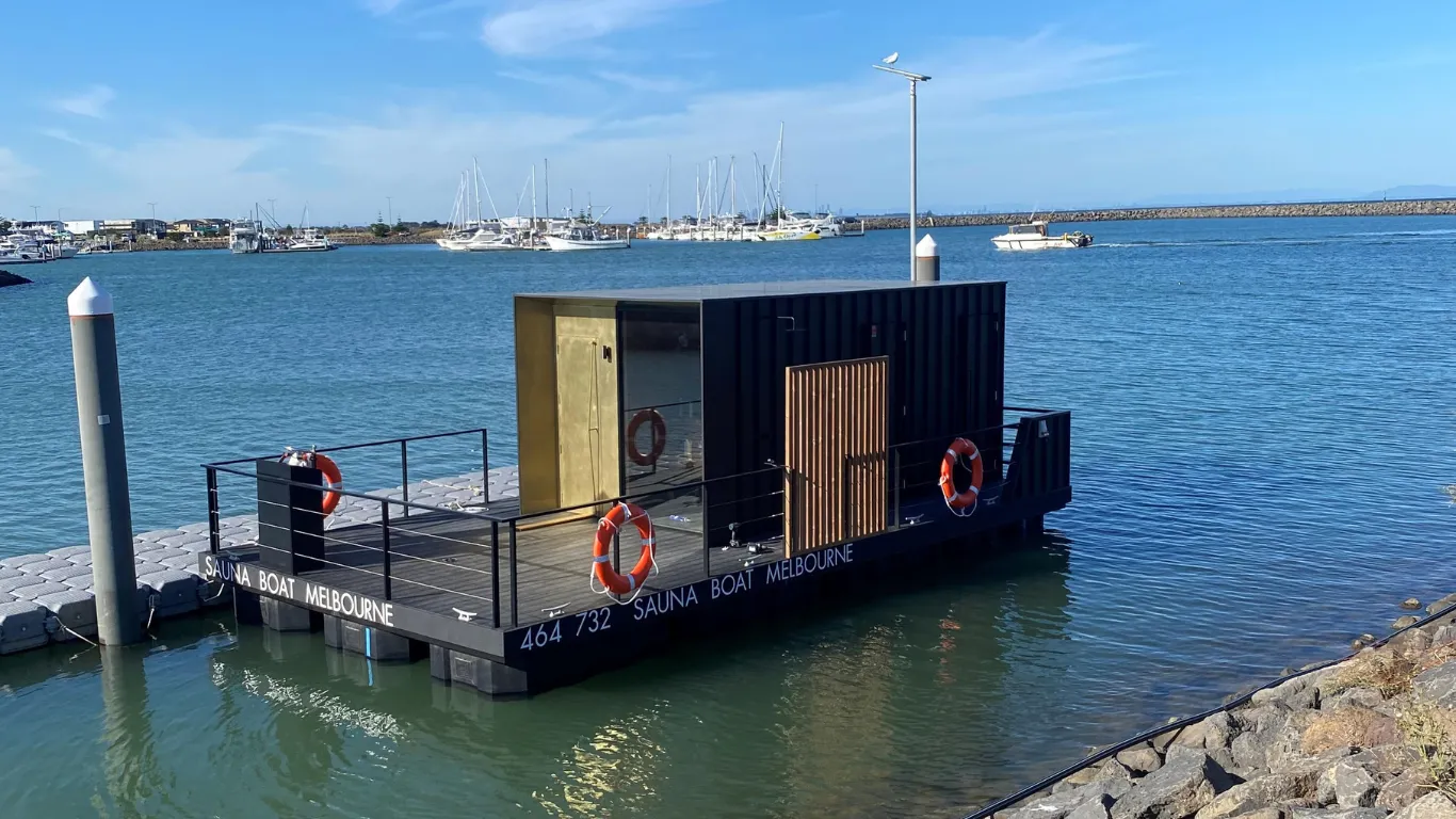 A floating sauna boat docked at a marina.
