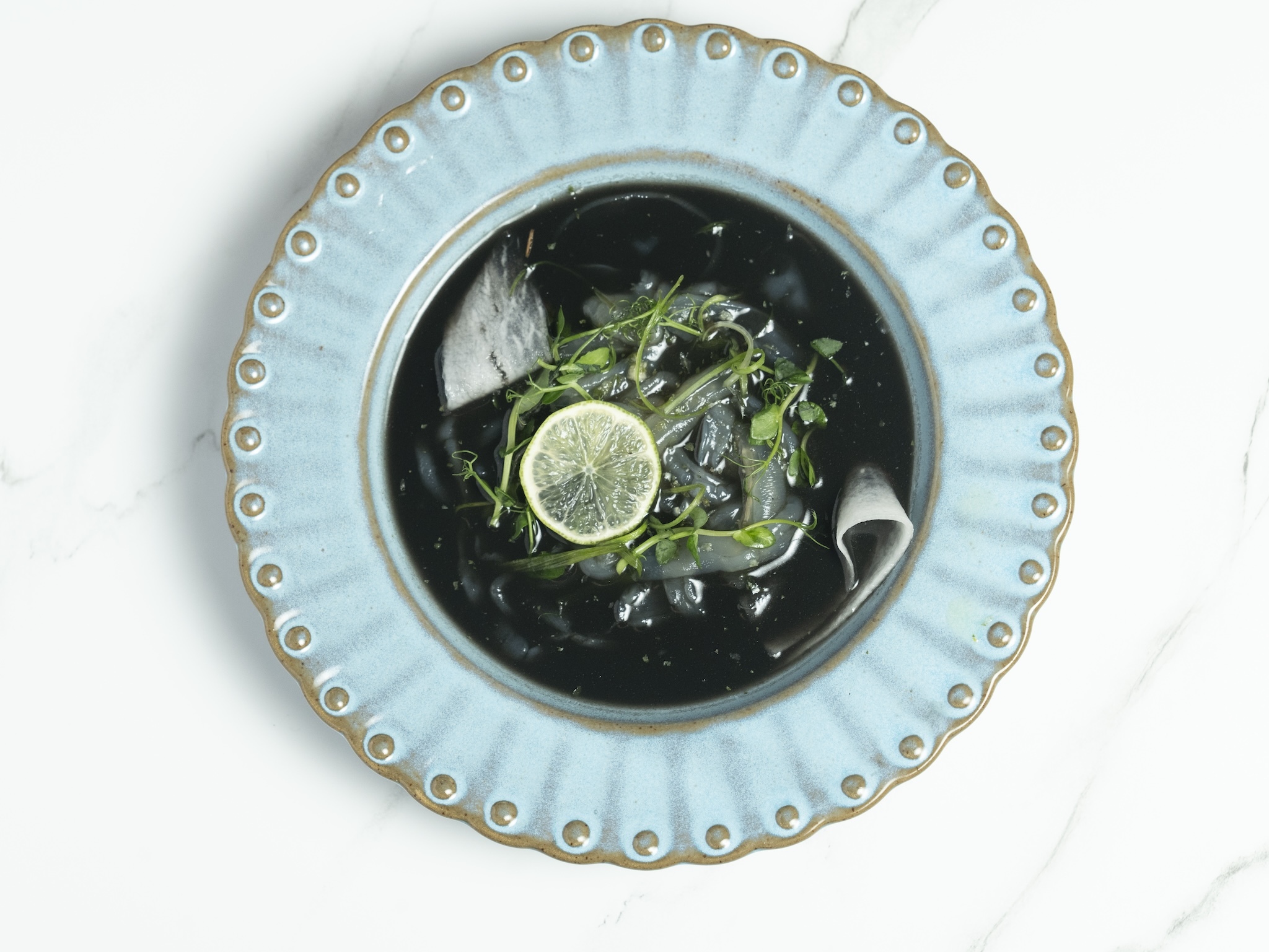 A black soup with cilantro with radish