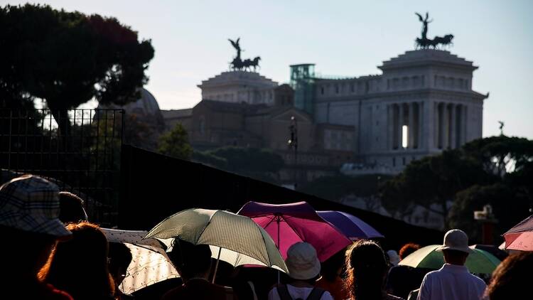Tourists in Rome with umbrellas to shield from sun