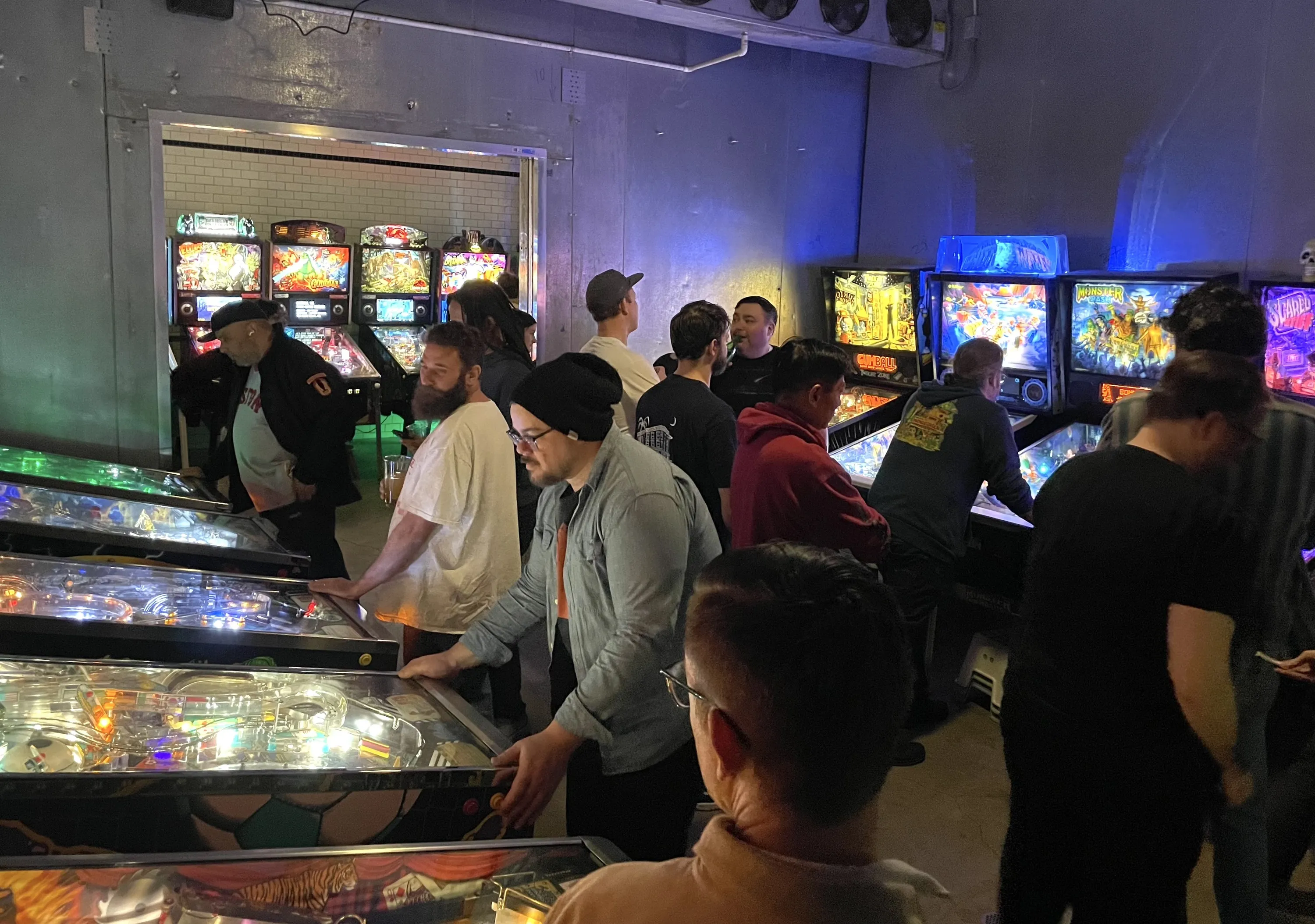 People play pinball in a bar.