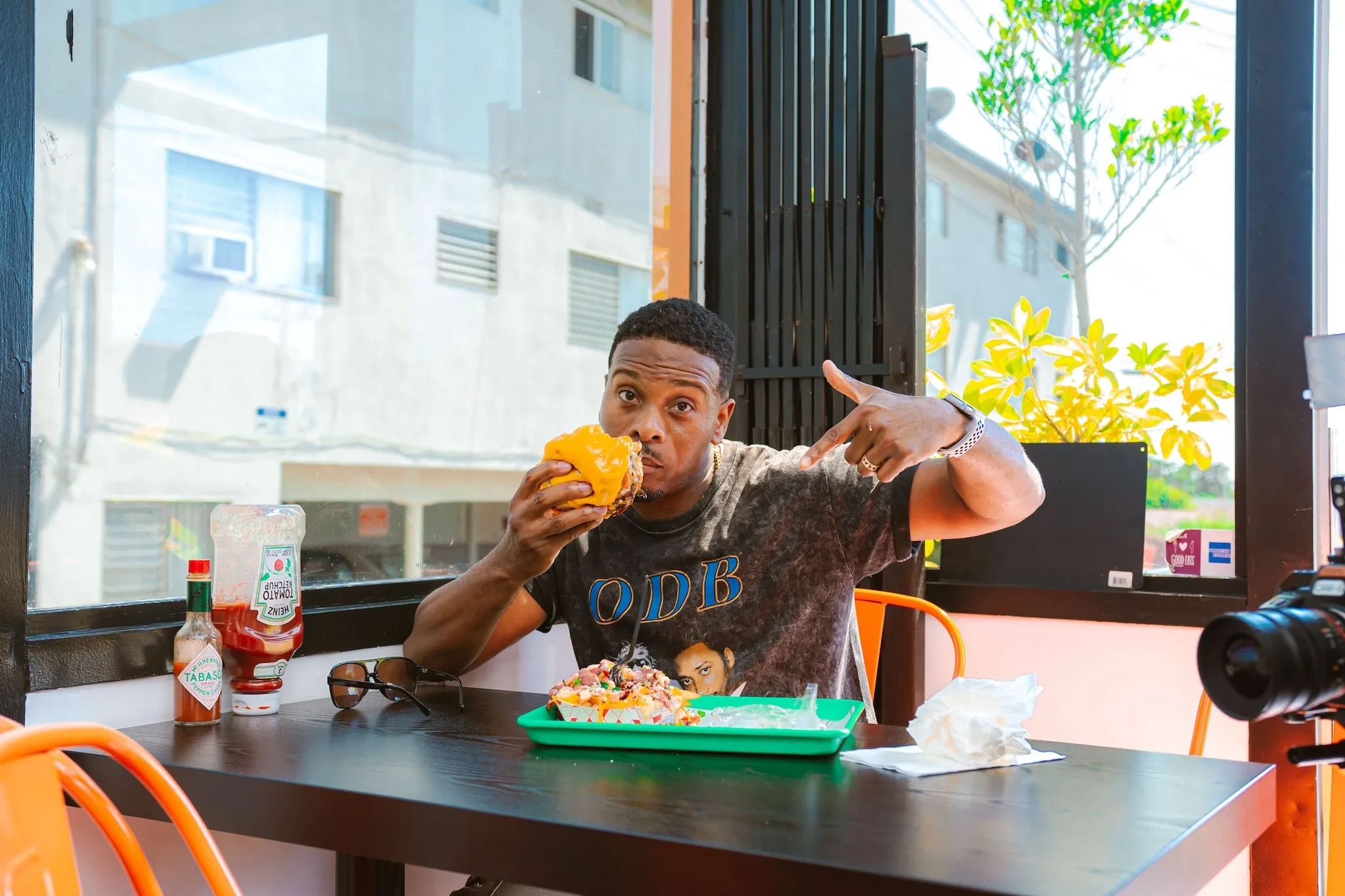 Kel Mitchell eating and pointing at a burger