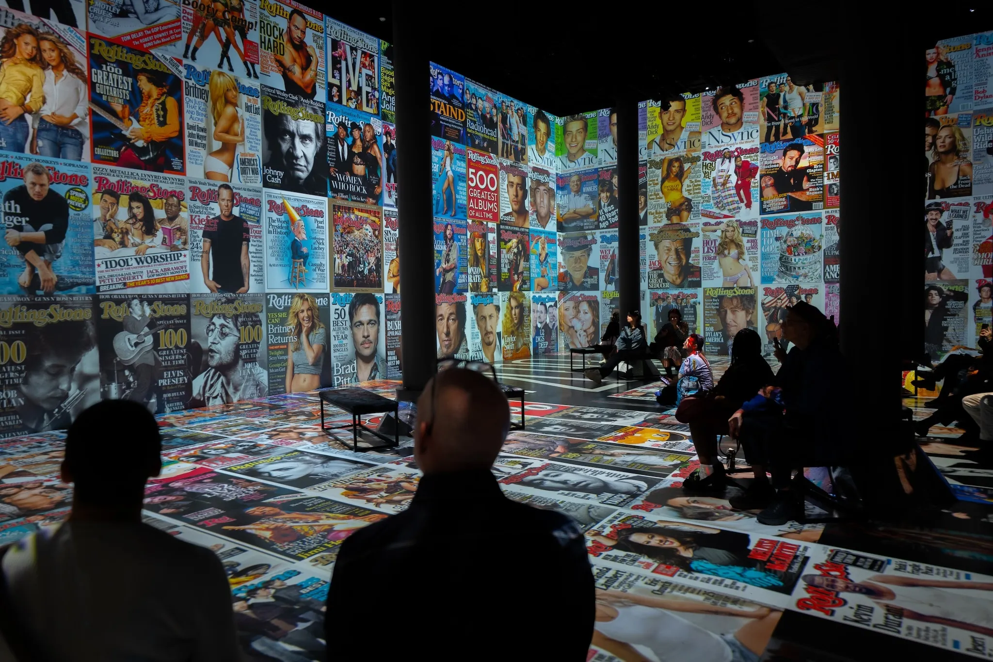 Rolling Stone magazine covers are project on a wall and floor.