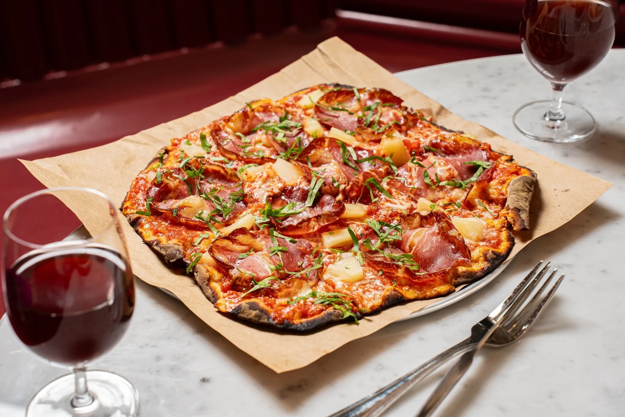 A thin crust Hawaiian pizza with coppa and pineapples
