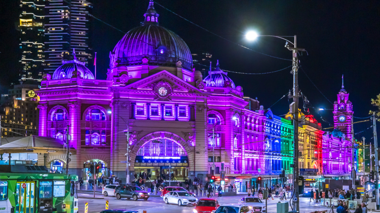 Flinders Street Station at night illuminated by rainbow lights.