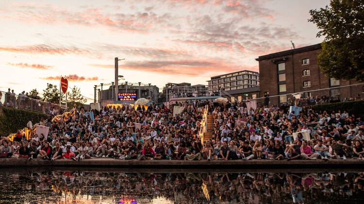Large crowds sitting on the steps by Regent's Canal and Granary Square watching a film at Everyman on the C