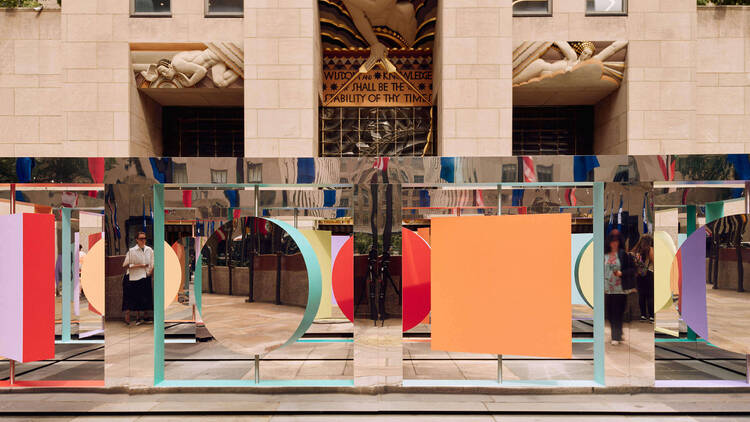 A colorful mirrored art installation in front of Rockefeller Center.