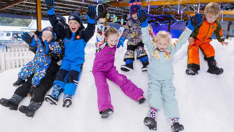 Kids sliding down a snow pile.