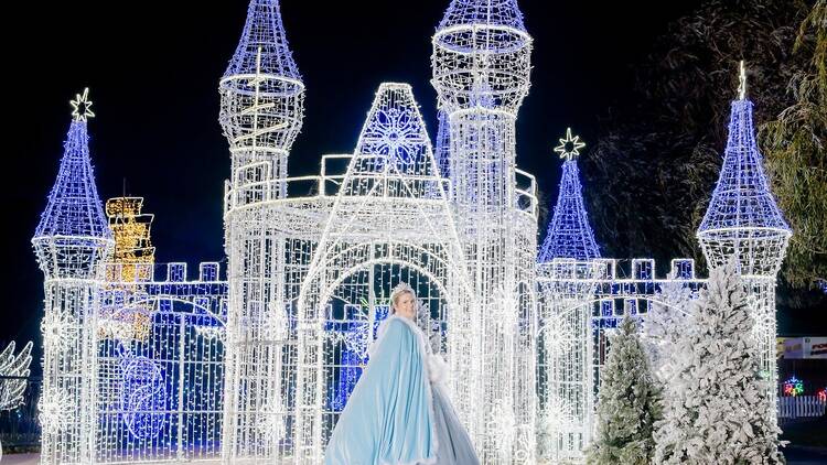 An illuminated castle with a princess out the front.