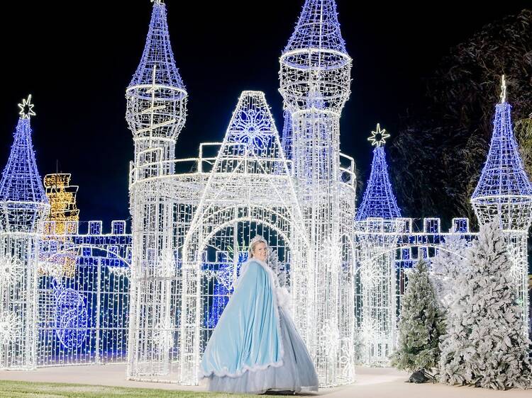 An illuminated castle with a princess out the front.