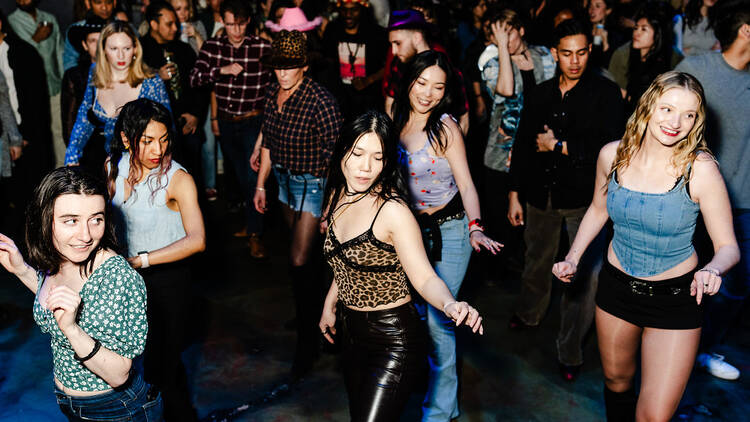 A group of people line dancing at a bar