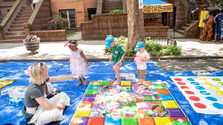 A mother and three young children play games such as Twister outside A mother and three young children play games such as Twister outside
