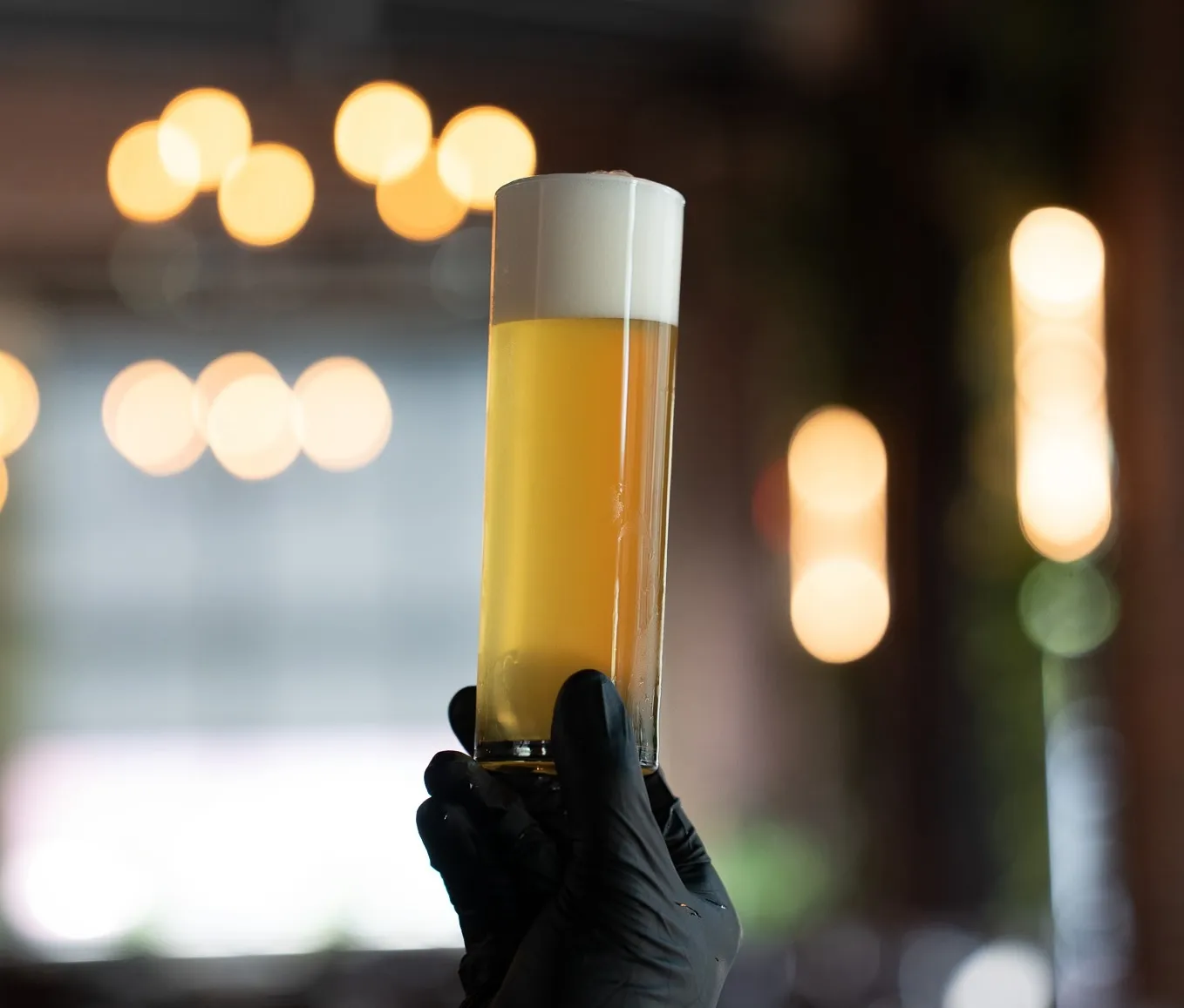 A person holding a beer with a glove on