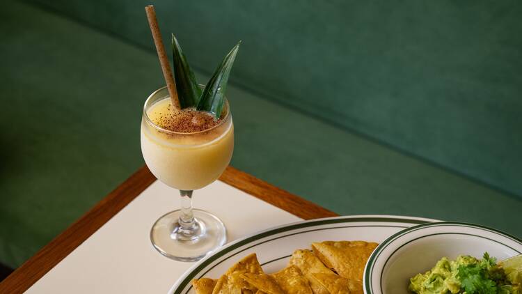 A frozen yellow cocktail with a palm frond