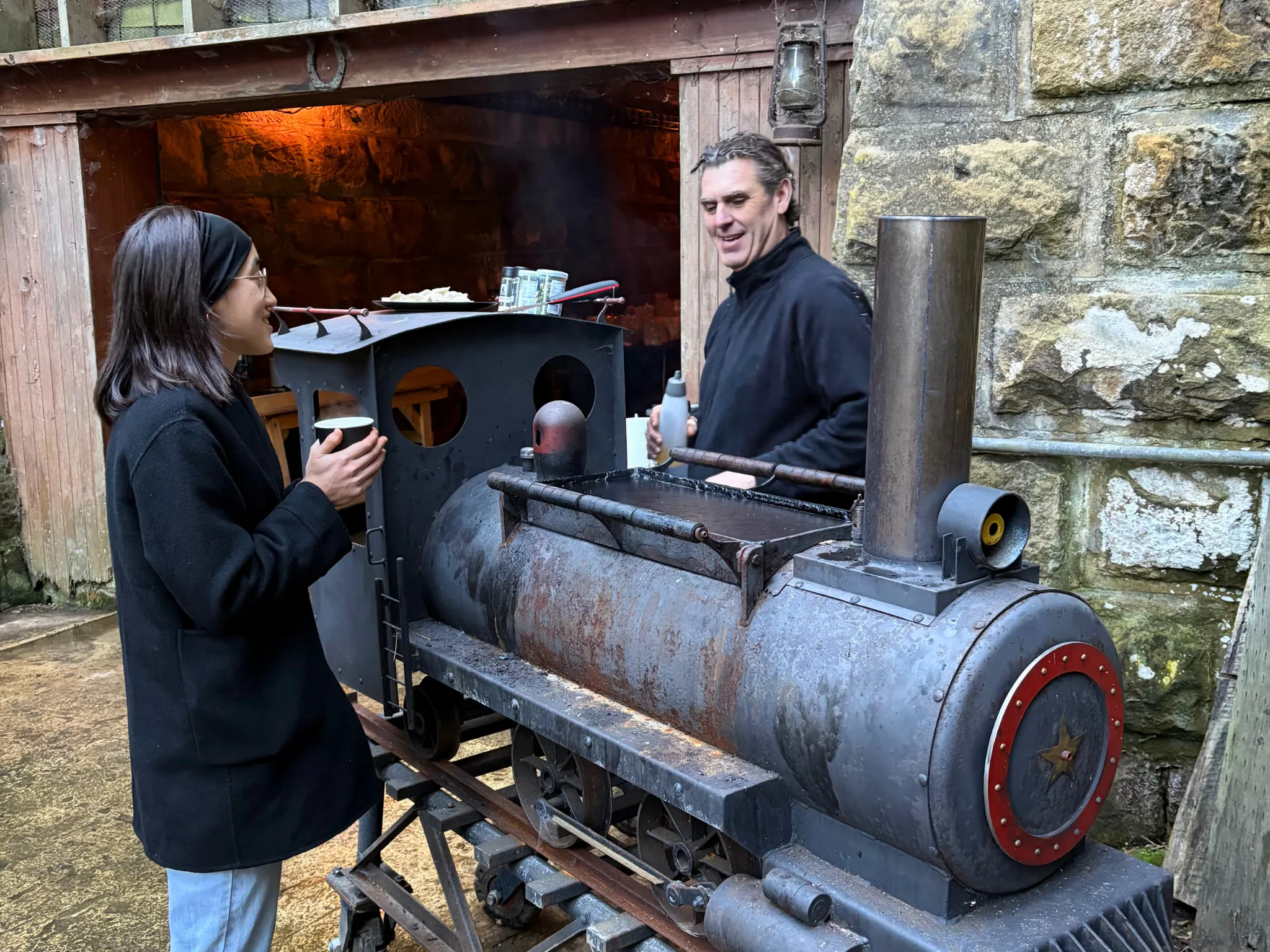 People gathered around train-shaped barbecue