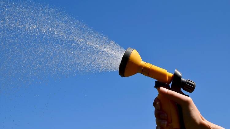 A hosepipe spraying against a blue sky