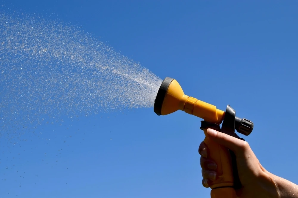 A hosepipe spraying against a blue sky