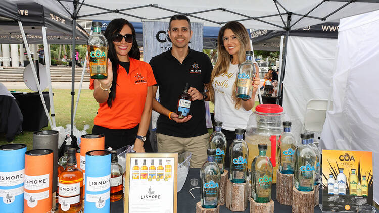 Three people holding liquor bottles