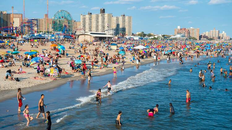 Crowds of people flock to the Coney Island beach and boardwalk on a hot summer weekend.