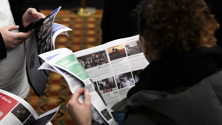 People flicking through programs