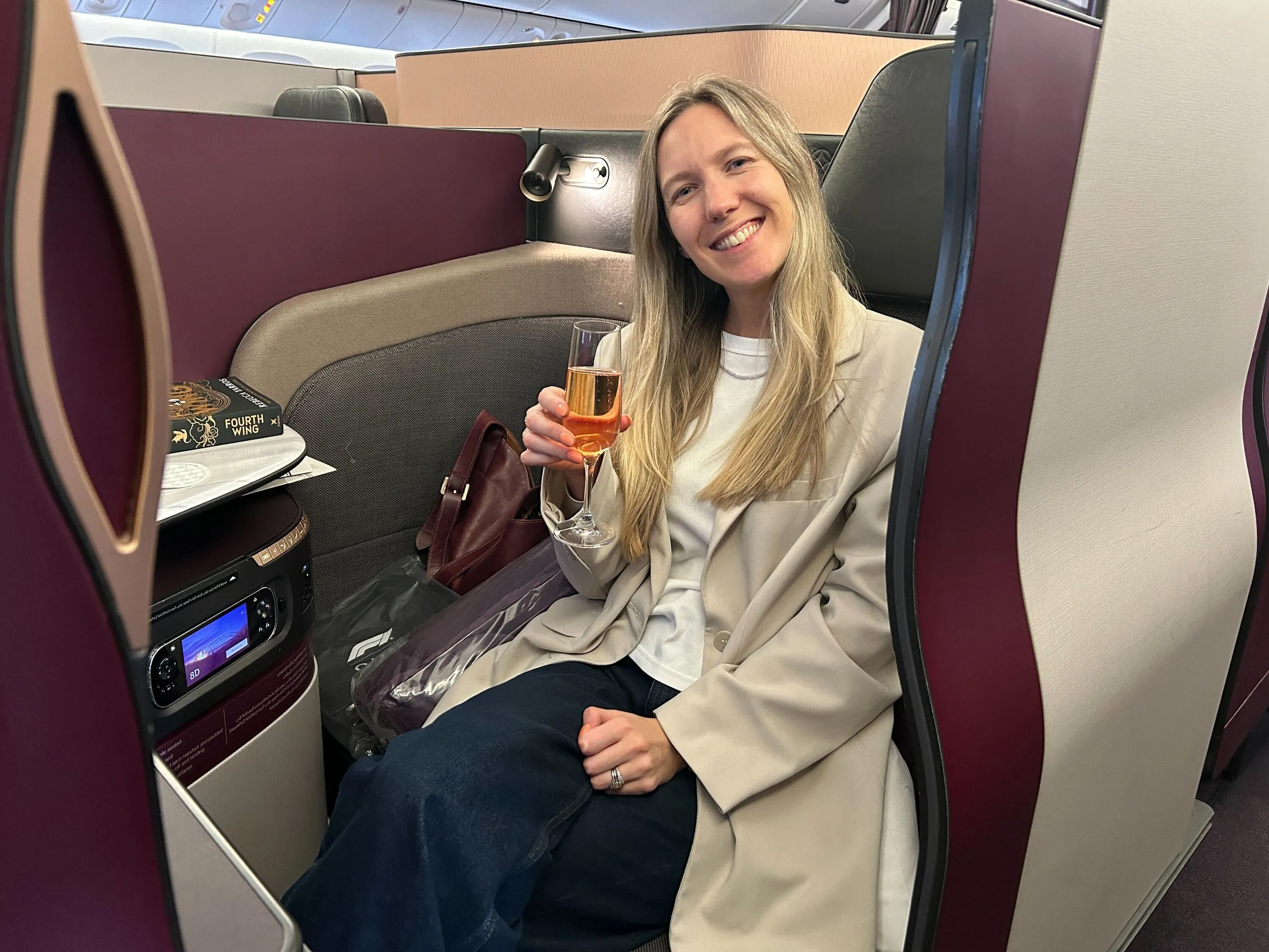 A blonde woman sitting in the Qatar Airways' Qsuite.
