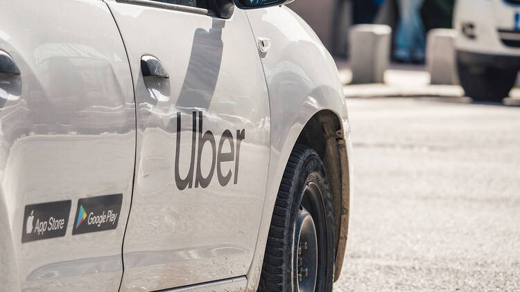 Car with the logo of the ride hailing company Uber in traffic.