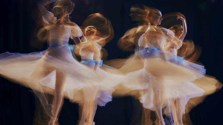 Young ballet ensemble in sheer dresses creating illusion of multiple movements against a dark background on stage. Concept of beauty, classic and modernity, contemporary art. Ad