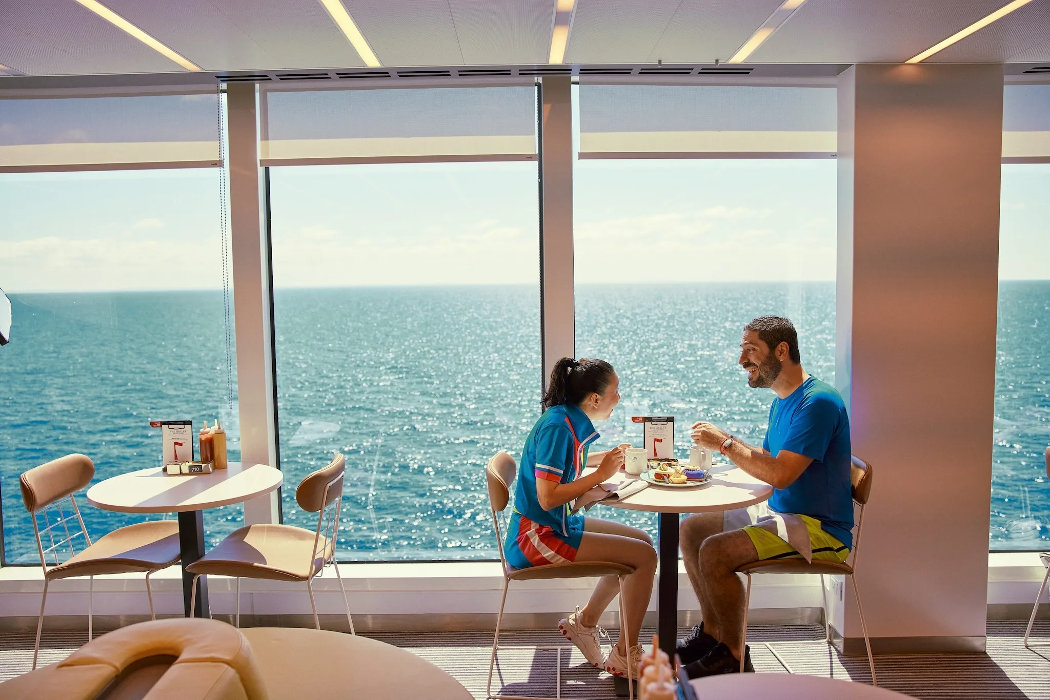 Two people dining near a window on a cruise ship that overlooks the ocean