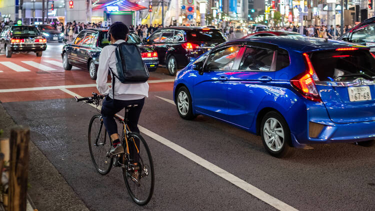 Man cycling in Shibuya at night