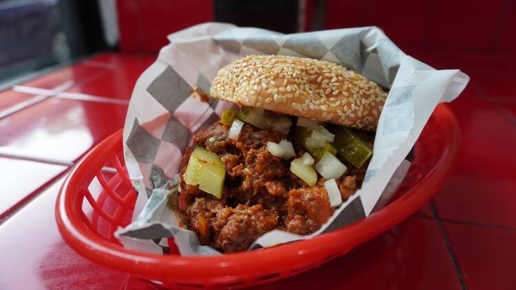 A sloppy joe in a black and white checkered paper wrapping inside a red basket tray