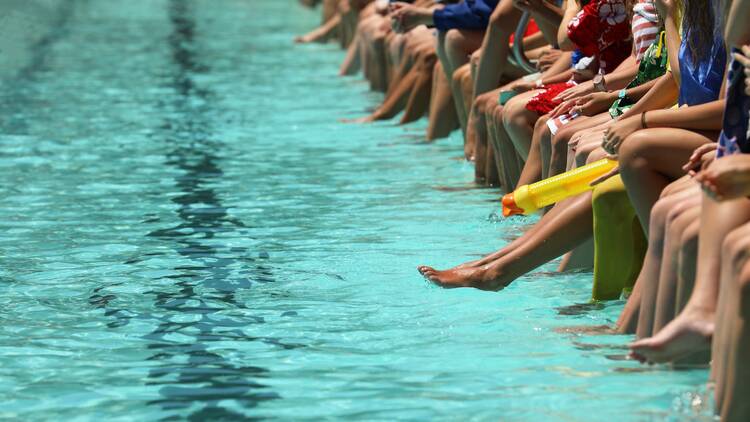 People sitting on the edge of a public pool