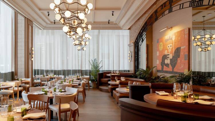 Interior of Cuerno with wooden tables, tan booths and a mural of a skeleton 