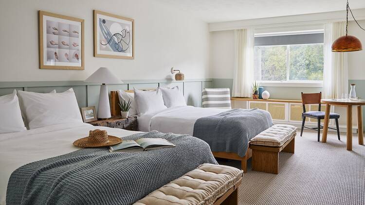 Two beds inside a hotel room with blue and green decor.
