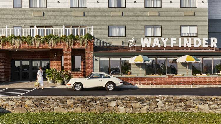 The exterior of Wayfinder Newport hotel with a vintage car out front.