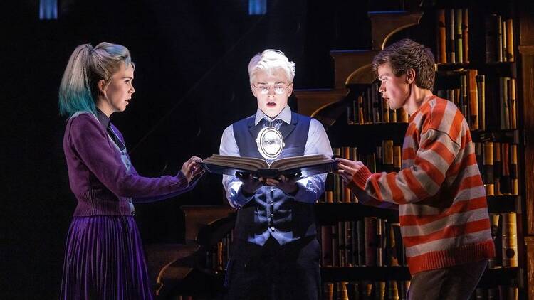 three people looking at a book