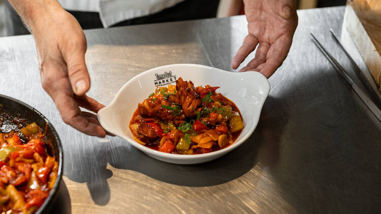 1. Chef István Pesti plates a vibrant serving of traditional Hungarian stew (lecsó) at Time Out Market Budapest, featuring colorful peppers and sausage in a rich paprika sauce