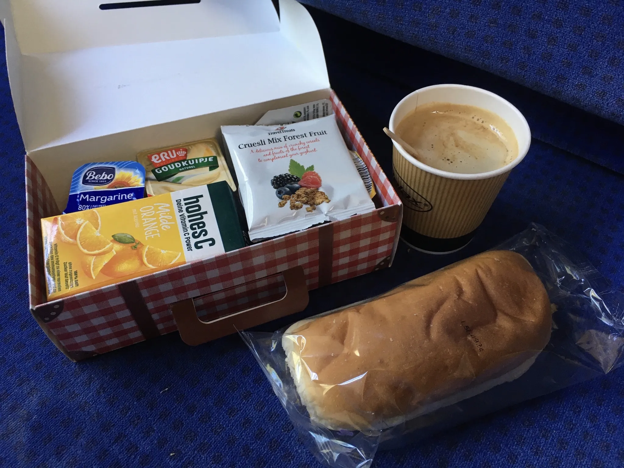 A coffee, sandwich and box of breakfast stuff