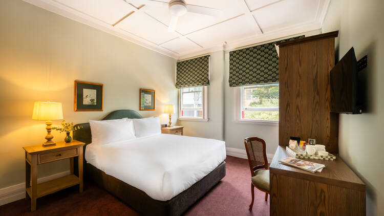 A hotel room with a double bed and desk 