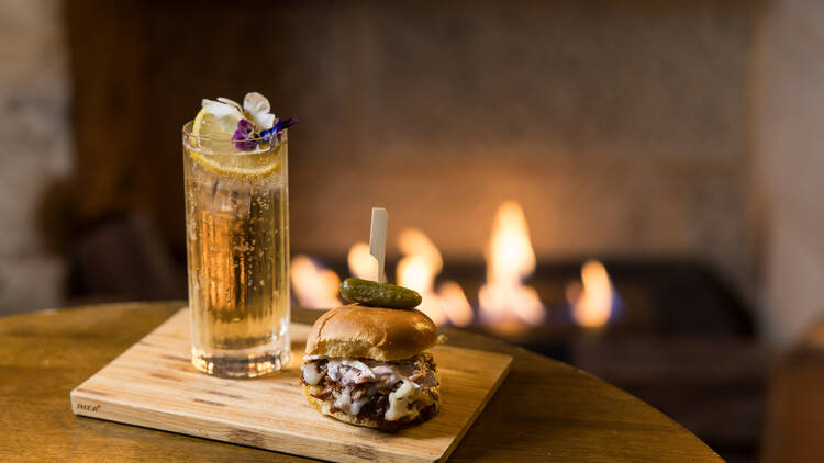 A cocktail and slider in front of a fireplace