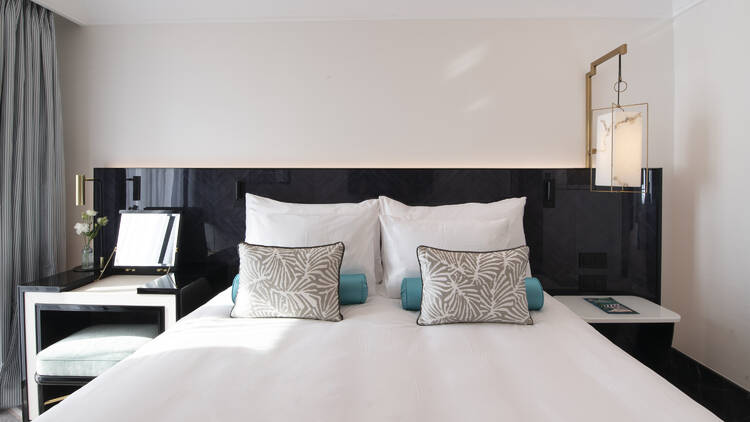 Maison Ablar bedroom showing two cushions and two pillows on a bed with black bedframe
