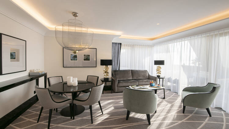 A view of the Victoria Suite interiors at Maison Ablar, showing a table and chairs and a sofa with grey carpet