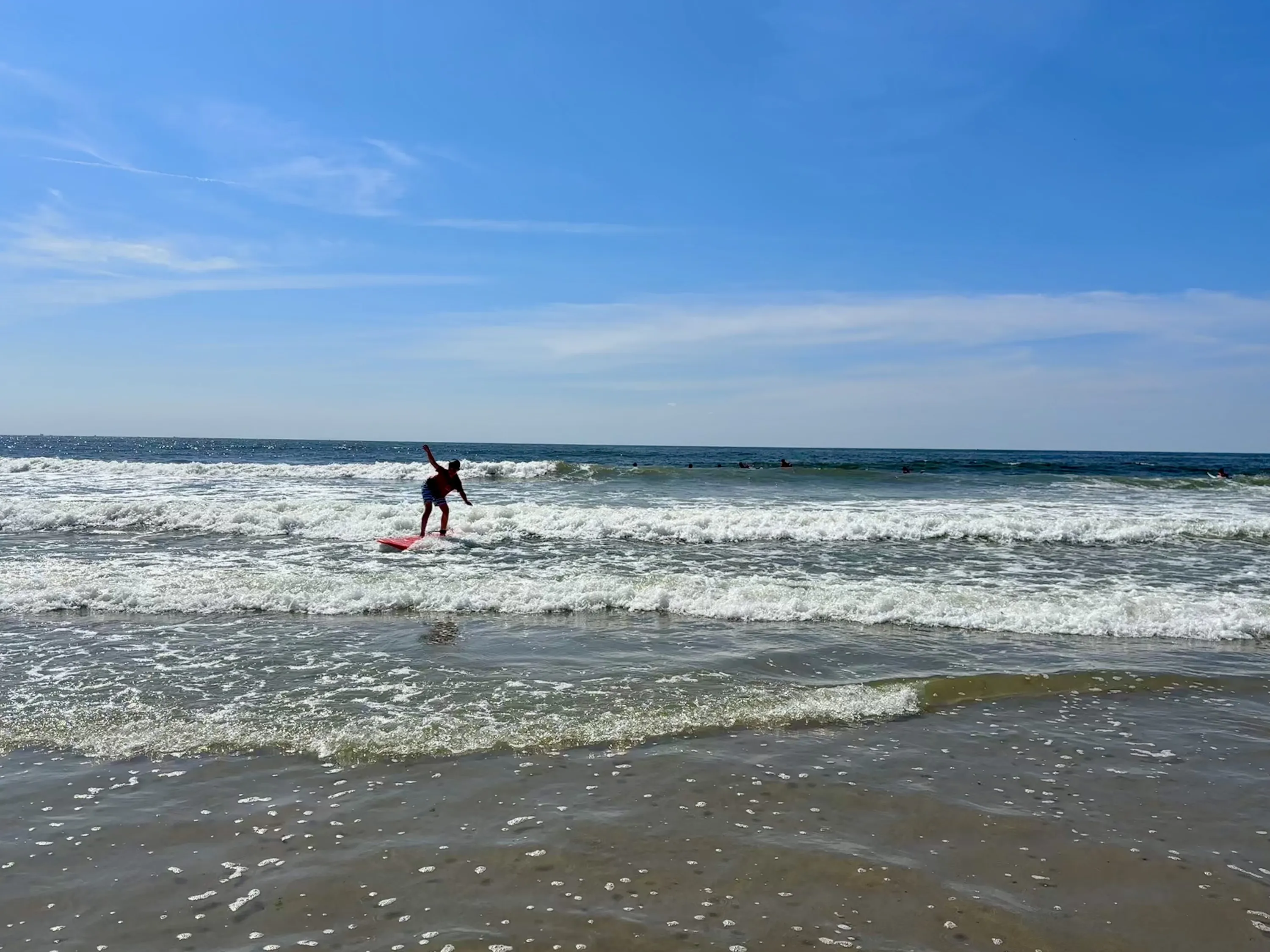 A kid surfs in the Atlantic Ocean with Black Surfing Rockaway.