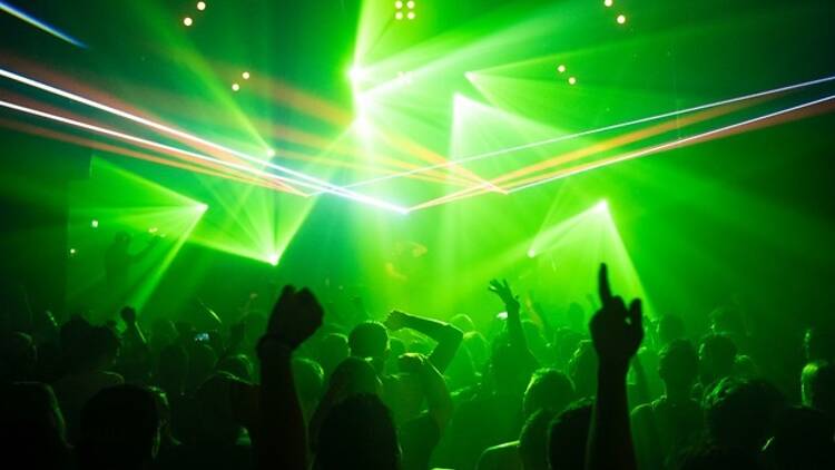 A club filled with people dancing and a bright green light with lasers.