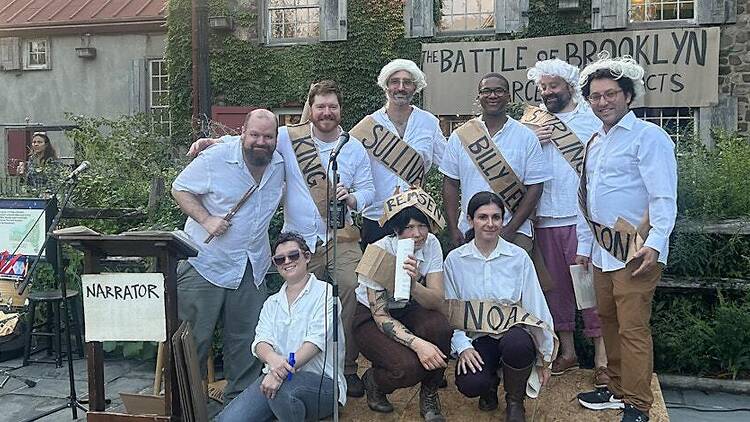 Actors dressed in old-timey costumes and sashes in Battle of Brookyln performance