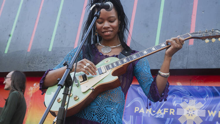 A woman playing a guitar in front of a microphone