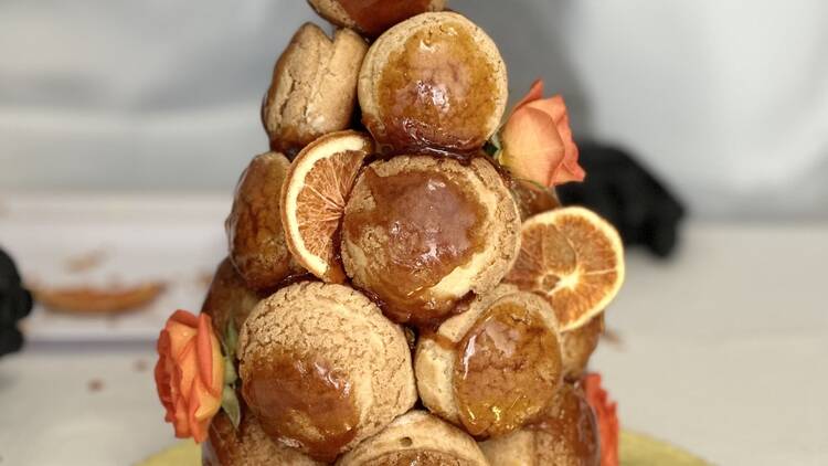 A tower of croquembouche decorated with orange slices and orange flowers