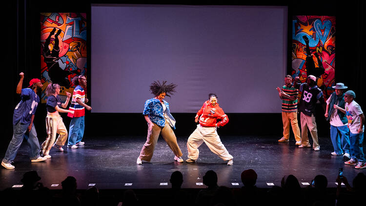 People on stage dancing - 2 dancing in the middle with 7 people surrounding them