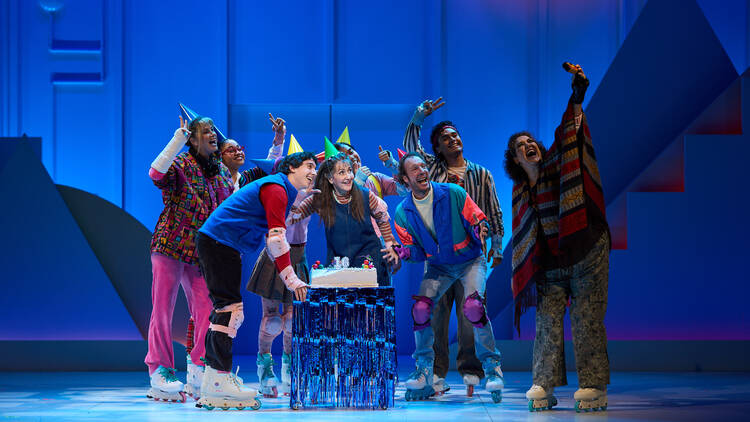 The cast of 'Kimberly Akimbo' on stage gathered around a cake wearing party hats.