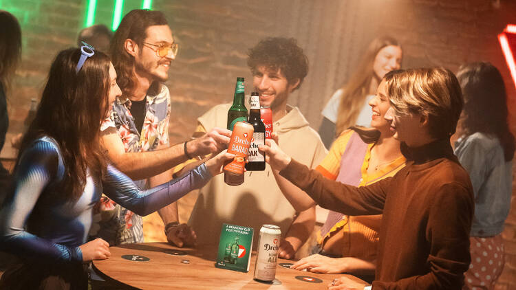 Laughter rises as cold Dreher beers clink together over the bar table — a simple, golden toast to good company. 